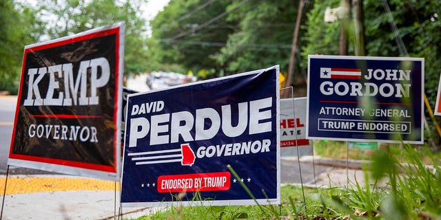 Campaign signs for Republican Georgia Gov. Brian Kemp and former Republican Georgia Sen. David Perdue on the side of the road.