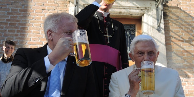 The retired Pope Benedict XVI and the premier of the state of Bavaria, Horst Seehofer, drink a glass of beer in the Vatican Garden in Vatican City. Benedict's private secretary Georg Gaenswein stands behind the two. 