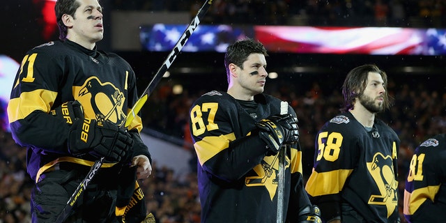 (L-R) Evgeni Malkin #71, Sidney Crosby #87, Kris Letang #58 of the Pittsburgh Penguins and their teammates line up for the singing of the National Anthem prior to the 2019 Coors Light NHL Stadium Series game between the Pittsburgh Penguins and the Philadelphia Flyers at Lincoln Financial Field on February 23, 2019 in Philadelphia.