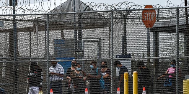 Migrants mostly form Central America wait in line to cross the border into the US at the Gateway International Bridge, between the cities of Brownsville, Texas, and Matamoros, Mexico, on March 15, 2021, in Brownsville, Texas. 