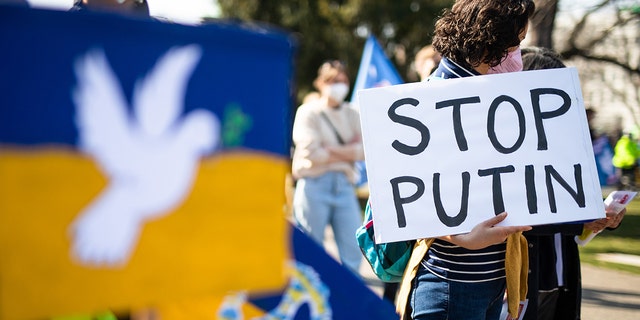 During a demonstration in the upper garden of the castle against the Russian military deployment in Ukraine, a woman holds a sign with the inscription ""Stop Putin""    in his hand on March 13, 2022. 