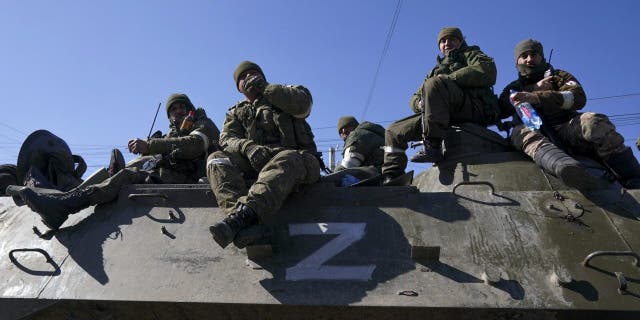 Russian forces and pro-Russian separatists watch as civilians flee the Ukrainian city of Mariupol along a humanitarian corridor, March 24, 2022.