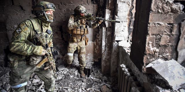 Russian soldiers patrol at the Mariupol drama theatre, bombed last March 16, on April 12, 2022 in Mariupol, as Russian troops intensify a campaign to take the strategic port city, part of an anticipated massive onslaught across eastern Ukraine, while Russia's President makes a defiant case for the war on Russia's neighbour. - *EDITOR'S NOTE: This picture was taken during a trip organized by the Russian military.*