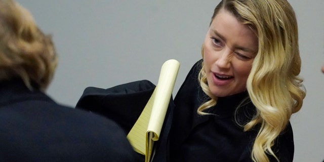 Actress Amber Heard winks at her attorney Elaine Bredehoft as her trial with ex-husband actor Johnny Depp breaks for lunch at the Fairfax County Circuit Courthouse in Fairfax, Va., April 18, 2022.