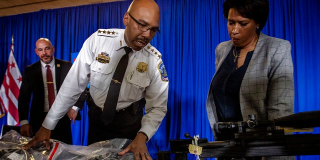 City officials including Mayor Muriel Bowser, right, Police Chief Robert J. Contee III, center and Deputy Mayor for Public  Safety Chris Geldart, left, with the guns collected from the shooter who terrorized the Van Ness area after discussing the rising violence at a press conference, in Washington, DC.  