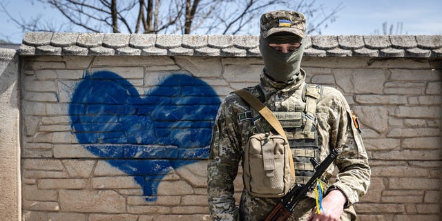 A Ukrainian soldier poses for a photo in front of a wall of heart graffiti during his patrol in an undisclosed location in Kharkiv oblast.