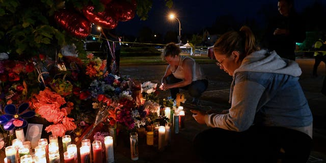 People light candles at a makeshift memorial near a Tops Grocery store in Buffalo, Nueva York, en mayo 15, 2022, the day after a gunman shot dead 10 gente. - Grieving residents from the US city of Buffalo held vigils Sunday after a white gunman who officials have deemed "pure evil" shot dead 10 people at a grocery store in a racially-motivated rampage (Photo by Usman KHAN / AFP) (Photo by USMAN KHAN/AFP via Getty Images)