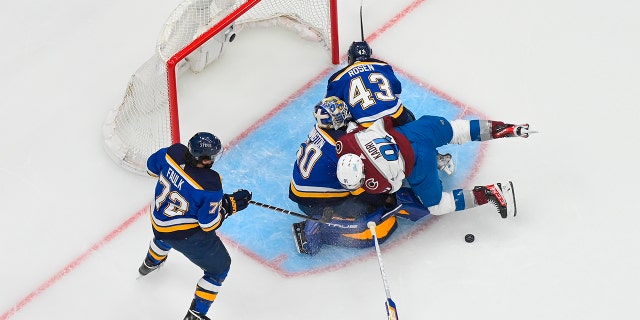 Nazem Kadri (91) of the Colorado Avalanche collides with Jordan Binnington (50) and Calle Rosen (43) of the St. Louis Blues in Game 3 of the second round of the 2022 Stanley Cup Playoffs at the Enterprise Center May 21, 2022, in St. Louis.