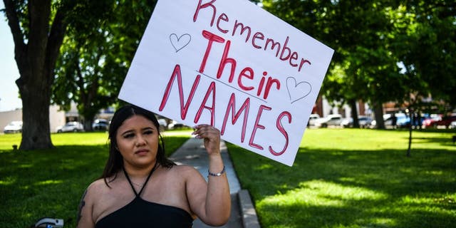 A local resident holds a placard as people grieve for the victims of the mass shooting at Robb Elementary School in Uvalde, Texas, on May 25, 2022.