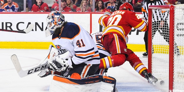 Blake Coleman of the Flames kicks the puck past Mike Smith of the Edmonton Oilers during Game 5 of the Stanley Cup playoff series at Scotiabank Saddledome on May 26, 2022, in Calgary, Alberta.