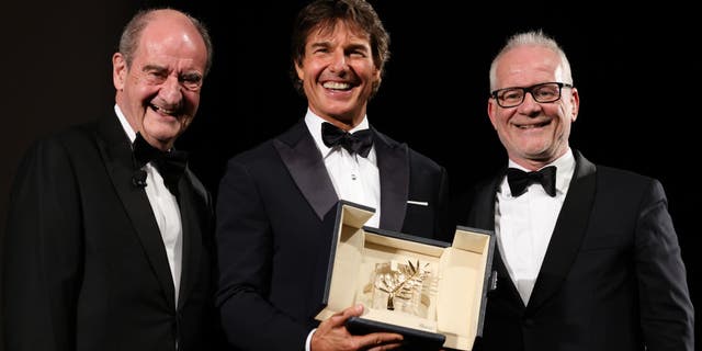 Pierre Lescure and Cannes Film Festival director Thierry Fremaux pose on stage with Tom Cruise (C) as he receives coveted award.