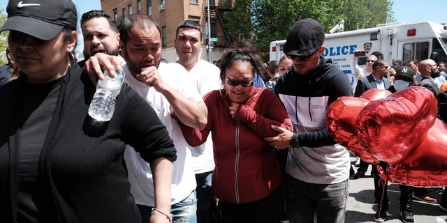 The parents of an 11-year-old girl in the South Bronx who was caught in gun crossfire on Monday and killed, grieve as they walk by her memorial during an anti violence rally on May 18, 2022 뉴욕시. 