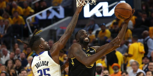 Draymond Green, right, of the Golden State Warriors, shoots a layup against Reggie Bullock (25) of the Dallas Mavericks during the third quarter in Game 1 of the 2022 NBA Western Conference finals at Chase Center in San Francisco May 18, 2022.