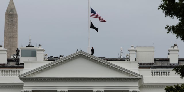 WASHINGTON, DC - MAY 24: A U.S. Secret Service officer lowers the American flag to half staff over the White House following the recent mass shooting at a Texas elementary school on May 24, 2022 in Washington, DC.  (Photo by Anna Moneymaker/Getty Images)