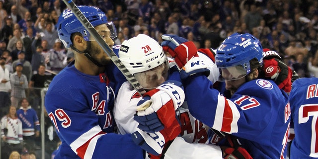 K'Andre Miller and Kevin Rooney of the Rangers stop Ian Cole of the Carolina Hurricanes on May 24, 2022 in New York City.