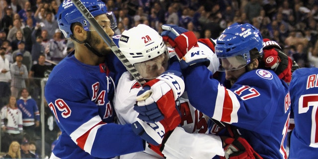 Andre Miller dan Kevin Rooney dari Rangers bertarung melawan Ian Cole dari Carolina Hurricane pada 24 Mei 2022 di New York City.