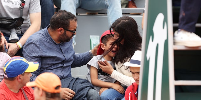 Parents comfort their child during the French Open at Roland Garros on May 26, 2022.