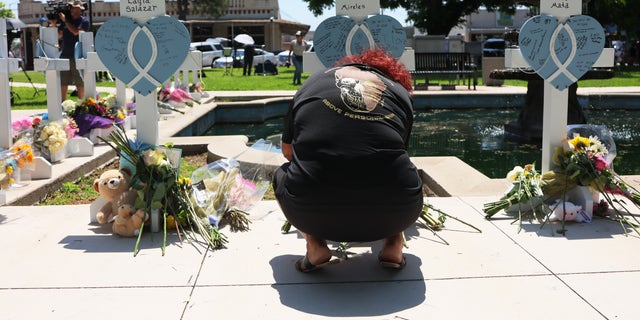 Un doliente se arrodilla en un monumento a una de las víctimas del tiroteo masivo del martes en una escuela primaria, en un parque a lo largo de Main Street el 26 de mayo de 2022, en Uvalde, Texas.