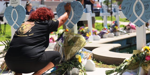 A mourner places her hand on a memorial for a victim of Tuesday's mass shooting at an elementary school, in City of Uvalde Town Square on May 26, 2022 in Uvalde, Texas. 