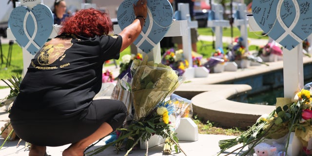 A mourner places her hand on a memorial for a victim of Tuesday's mass shooting at an elementary school, in City of Uvalde Town Square on May 26, 2022 in Uvalde, Texas. 