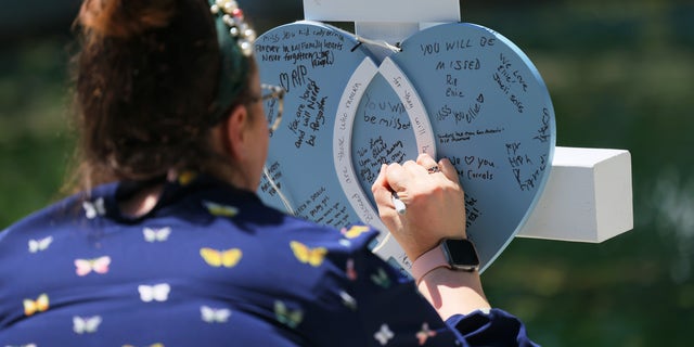 A mourner writes a message on memorial for a victim of Tuesday's mass shooting at an elementary school, in City of Uvalde Town Square on May 26, 2022 （乌瓦尔德）, 德州.