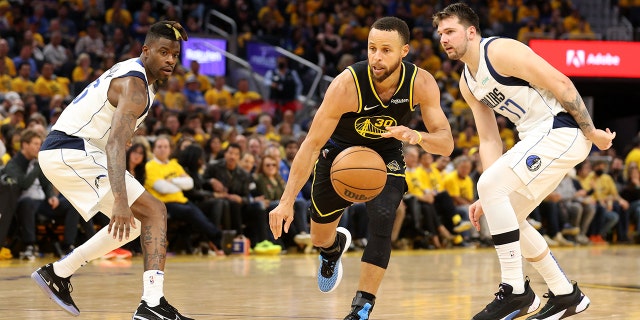 Stephen Curry (30) of the Golden State Warriors drives past Reggie Bullock (25) and Luka Doncic (77) of the Dallas Mavericks during the third quarter in Game 5 of the 2022 NBA Western Conference finals at Chase Center in San Francisco May 26, 2022. 