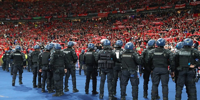 Riot police watch supporters of Liverpool FC during the UEFA Champions League final match between Liverpool FC and Real Madrid at Stade de France on May 28, 2022 in Paris, France. 