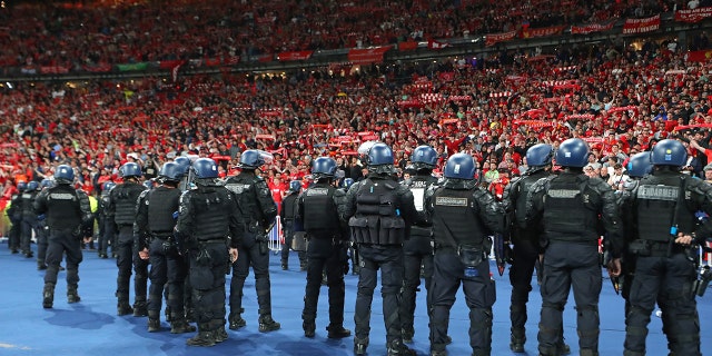 Riot police watch supporters of Liverpool FC during the UEFA Champions League final match between Liverpool FC and Real Madrid at Stade de France on May 28, 2022 in Paris, France.