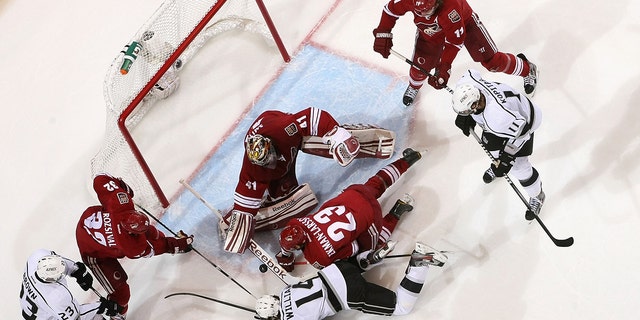 Goaltender Mike Smith of the Coyotes attempts to cover up the puck as Justin Williams of the Los Angeles Kings looks for a rebound in the 2012 NHL Stanley Cup Playoffs at Jobing.com Arena on May 22, 2012, in Glendale, Arizona.