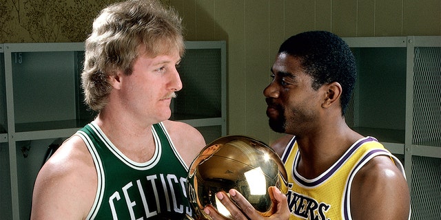 Larry Bird # 33 des Celtics de Boston pose pour un portrait avec Magic Johnson des Lakers de Los Angeles, chacun tenant le trophée du championnat NBA au Great Western Forum de Los Angeles, en Californie.  