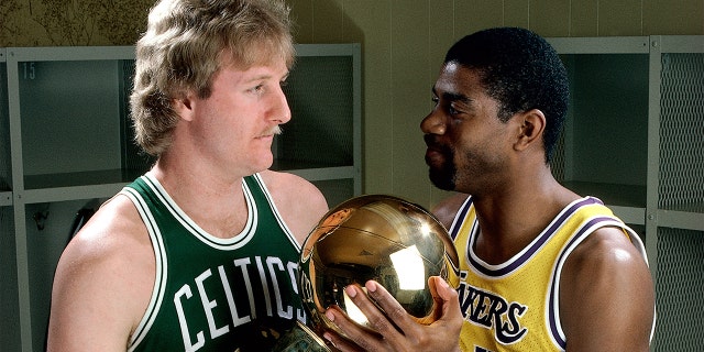 Larry Bird # 33 des Celtics de Boston pose pour un portrait avec Magic Johnson des Lakers de Los Angeles, chacun tenant le trophée du championnat NBA au Great Western Forum de Los Angeles, en Californie.  