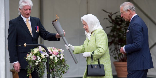 Queen Elizabeth accompanied by Prince Charles and Bruno Peek, Originator and pageant master as she lights a beacon to celebrate Her Majesty's birthday on April 21, 2016, in Windsor, England.