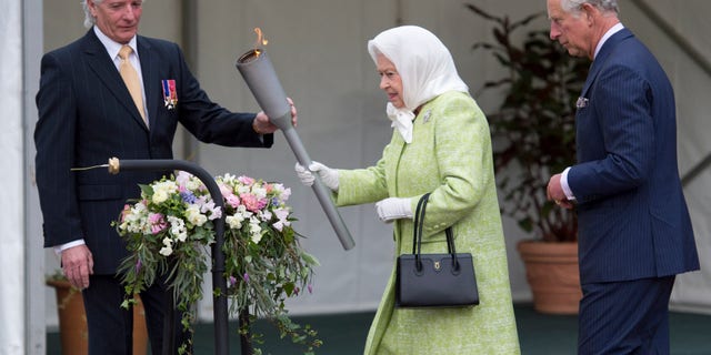 Queen Elizabeth accompanied by Prince Charles and Bruno Peek, Originator and pageant master as she lights a beacon to celebrate Her Majesty's birthday on April 21, 2016, in Windsor, England.