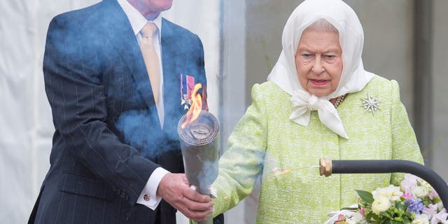 Bruno Peek hands Queen Elizabeth a torch for her to light the first beacon in honor of her 90th birthday in Windsor on April 21, 2016. Peek has served as the Queen's pageant master in both her Golden and Diamond Jubilees.