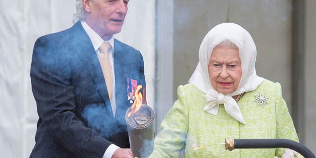 Bruno Peek hands Queen Elizabeth a torch for her to light the first beacon in honor of her 90th birthday in Windsor on April 21, 2016. Peek has served as the Queen's pageant master in both her Golden and Diamond Jubilees.