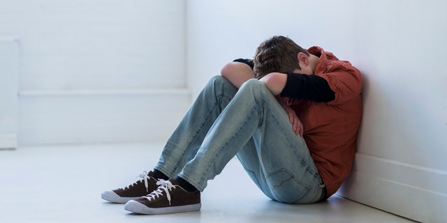 Stock image of a young man with his head down and depressed.