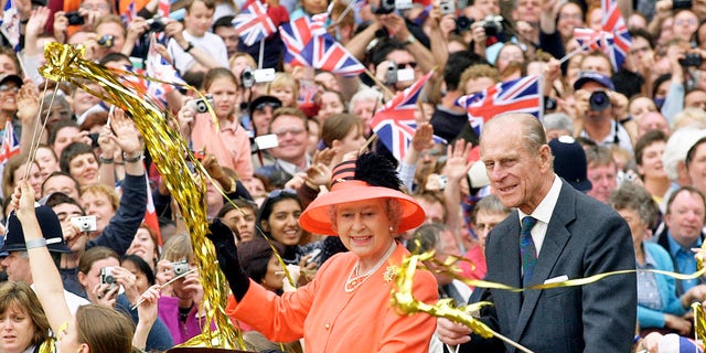 Queen Elizabeth and Prince Phillip ride along the Mall in an open-top car on their way to watch a parade in celebration of the Golden Jubilee in 2002.