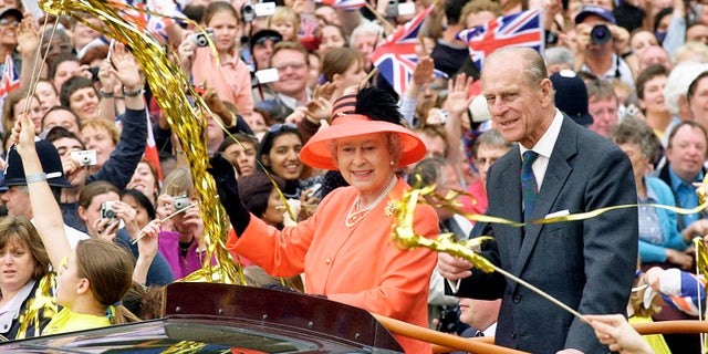 Queen Elizabeth and Prince Phillip ride along the Mall in an open-top car on their way to watch a parade in celebration of the Golden Jubilee in 2002.