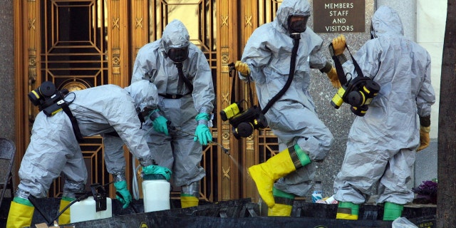 A hazardous material worker sprays his colleagues after they finished an anthrax search at Dirksen Senate Office Building Nov. 18, 2001, on Capitol Hill in Washington. 