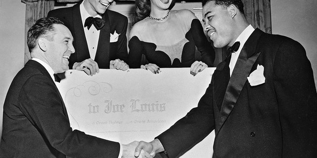 Heavyweight champion Joe Louis was honored as "a great fighter and a great American" at a dinner tendered to him by the Southern Conference for Human Welfare at the Waldorf Astoria Hotel in New York City Dec. 16, 1946. The champ is congratulated by Dr. Clark Foreman, left, president of the organization. Standing behind a giant scroll, inscribed with personal tributes from many celebrities, are Frank Sinatra, who acted as chairman and master of ceremonies at the dinner, and actress Carole Landis.