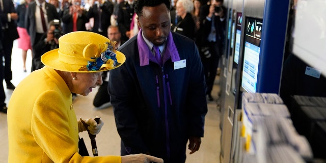 Queen Elizabeth II using an Oyster card machine as she attends the Elizabeth line's official opening at Paddington Station on May 17, 2022, in London, England.