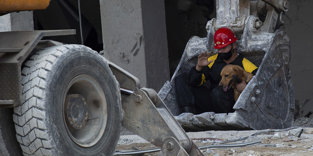 A rescue worker and his search dog are transported on the shovel of an excavator on Sunday, May 8, to search for survivors at the site of the Hotel Saratoga in Old Havana. 