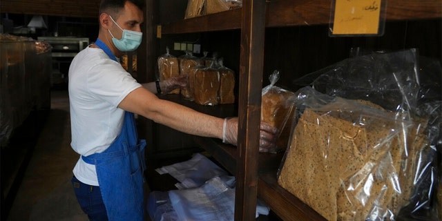 L'employé de la boulangerie Mojtaba Motallebi a mis des paquets de pain dans les étagères d'une boulangerie à Téhéran, en Iran, le mercredi 11 mai 2022.