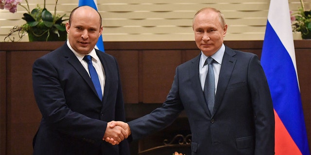 Russian President Vladimir Putin is shaking hands with former Israeli Prime Minister Naftali Bennett at a meeting in Sochi on October 22, 2021. 