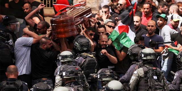 Family and friends carry the coffin of Al Jazeera reporter Shirin Abu Akleh, who was killed during an Israeli raid on occupied West Bank Jenin, after clashes erupted with Israeli security forces during his funeral in Jerusalem on May 13, 2022. 