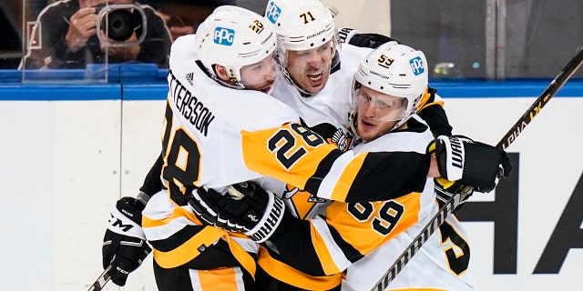 Pittsburgh Penguins' Jake Guentzel (59) celebrates with teammates Marcus Pettersson (28) and Evgeni Malkin (71) after scoring a goal during the second period of Game 5 of an NHL hockey Stanley Cup first-round playoff series against the New York Rangers Wednesday, May 11, 2022, in New York.