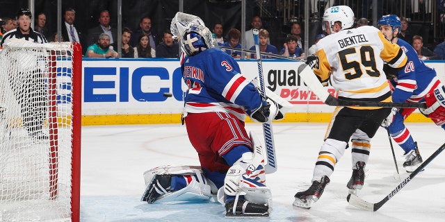 Jake Guentzel #59 of the Pittsburgh Penguins knocks the puck past goaltender Igor Shesterkin #31 of the New York Rangers during the second period in Game Seven of the First Round of the 2022 Stanley Cup Playoffs at Madison Square Garden on May 15, 2022 in New York City.
