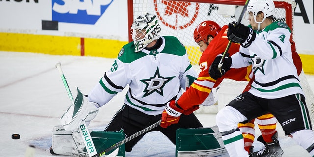 Dallas Stars goalie Jake Oettinger, 剩下, kicks the puck away from Calgary Flames left wing Milan Lucic, 中央, as Flames' Miro Heiskanen defends during the second period of Game 2 of an NHL hockey Stanley Cup first-round playoff series in Calgary, Alberta, 星期四, 可能 5, 2022. 