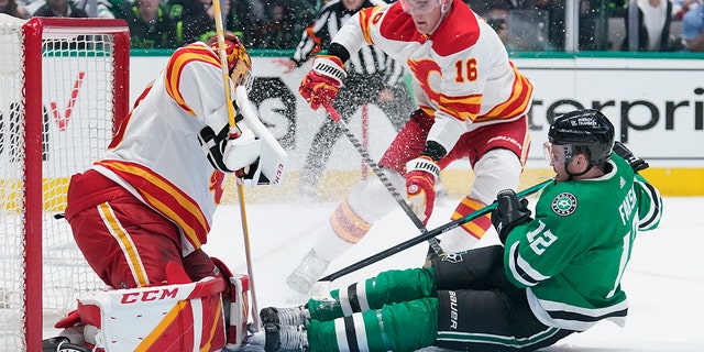 Dallas Stars center Radek Faksa (12) slides into Calgary Flames goaltender Jacob Markstrom, left, following a shot in the first period of Game 4 of an NHL hockey Stanley Cup first-round playoff series, Monday, May 9, 2022, in Dallas. Flames Nikita Zadorov is at center. 