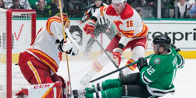 Dallas Stars center Radek Faksa (12) slides into Calgary Flames goaltender Jacob Markstrom, left, following a shot in the first period of Game 4 of an NHL hockey Stanley Cup first-round playoff series, Monday, May 9, 2022, in Dallas. Flames Nikita Zadorov is at center.